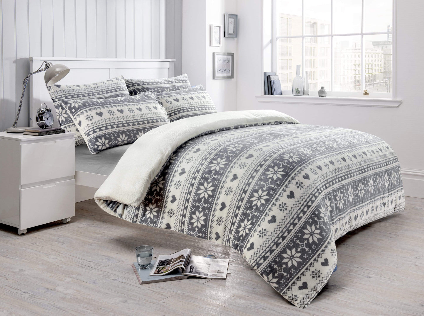 Bedroom with a bed featuring a patterned comforter and pillows, next to a nightstand.