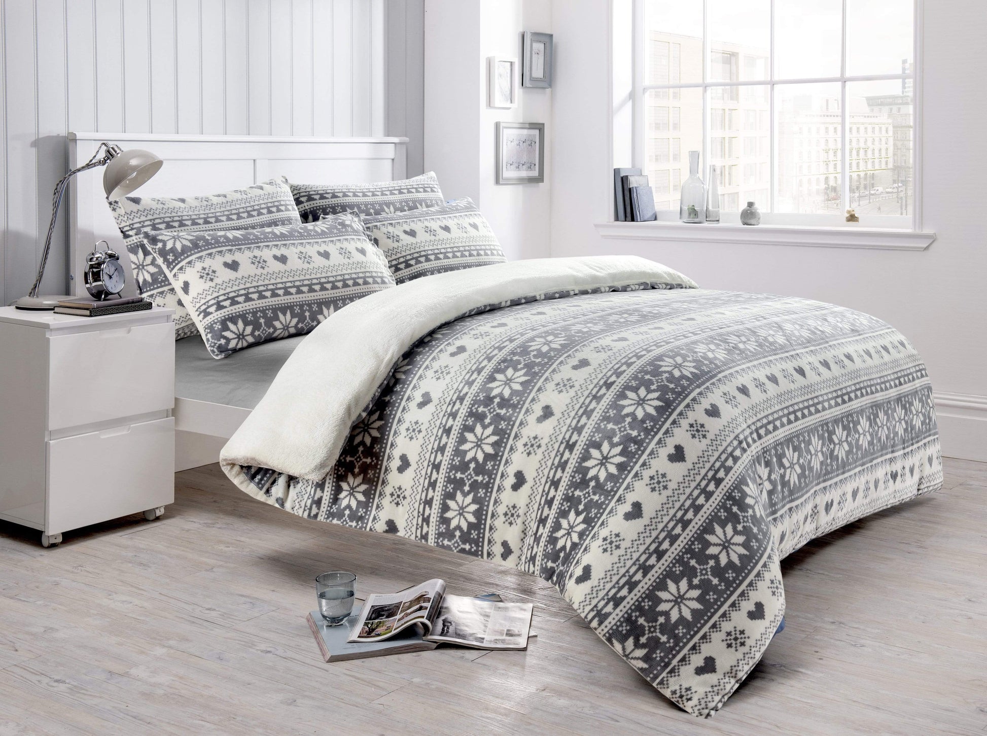 Bedroom with a bed featuring a patterned comforter and pillows, next to a nightstand.