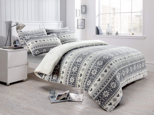 Bedroom with a bed featuring a patterned comforter and pillows, next to a nightstand.